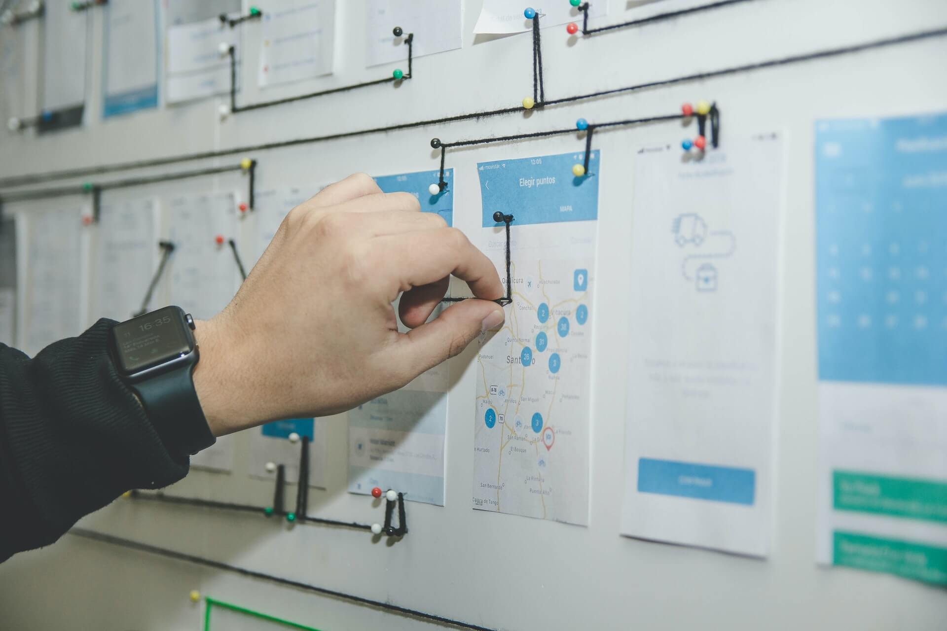 Hand of a human on a pinboard with target planning